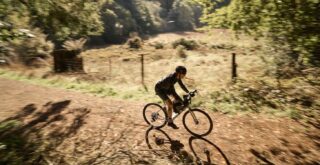 Four Corners 2 rider on a dirt road alongside a meadow.